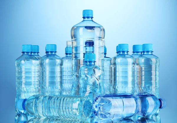 Diferentes botellas de agua sobre fondo azul — Foto de Stock