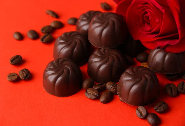 Шоколадные конфеты и кофейные зерна, на красном фоне — стоковое фото