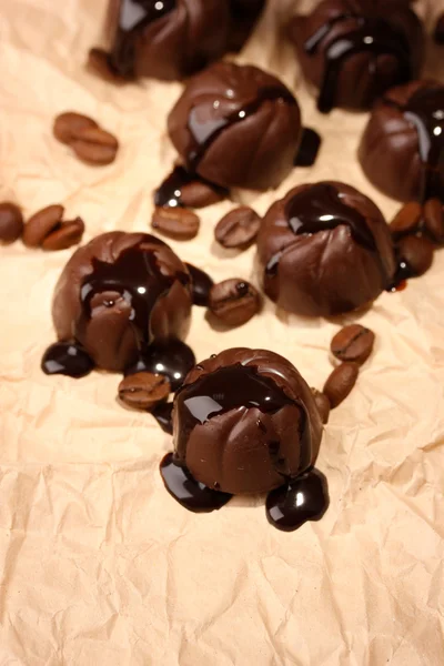 Chocolate candies and coffee beans, on beige paper background — Stock Photo, Image