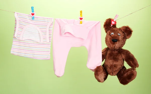 Baby clothes hanging on clothesline, on color background — Stock Photo, Image