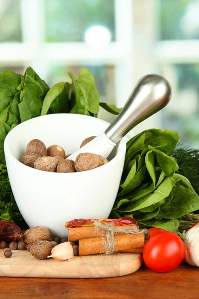 Composition of mortar, spices, tomatoes and green herbs, on bright background — Stock Photo, Image