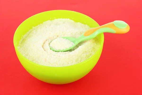 Powdered milk in bowl for baby and spoon on red background — Stock Photo, Image