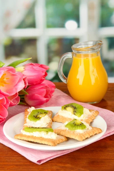 Canapés saborosos com queijo e kiwi, na placa de cor, no fundo brilhante — Fotografia de Stock