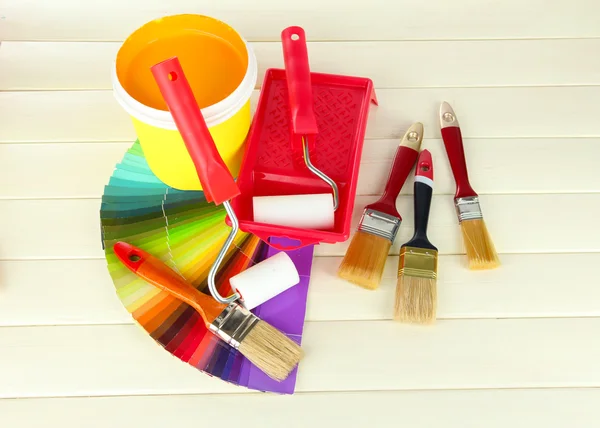 Set for painting: paint pot, brushes, paint-roller on white wooden table — Stock Photo, Image