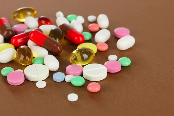 Assortment of pills, tablets and capsules on brown background — Stock Photo, Image