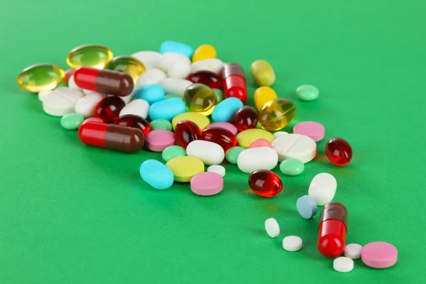 Assortment of pills, tablets and capsules on green background — Stock Photo, Image