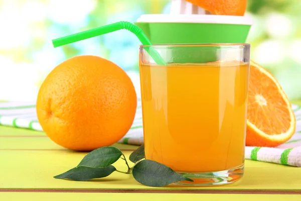 ジュース、柑橘類を押して、緑の木製テーブルに熟したオレンジ色のガラス — ストック写真