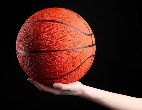 Basketball in woman hand on black background — Stock Photo, Image