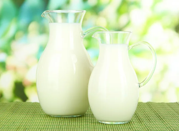 Pots de lait sur la table sur fond lumineux — Photo