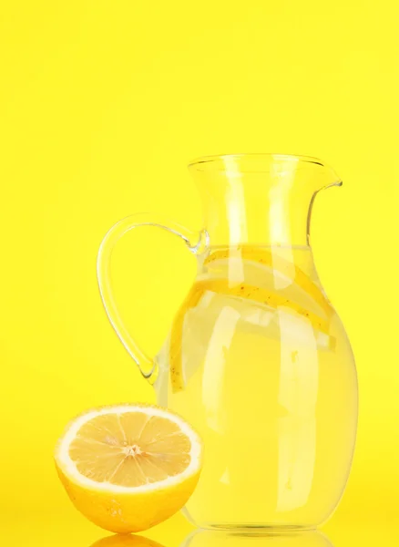 Lemonade in pitcher on yellow background — Stock Photo, Image