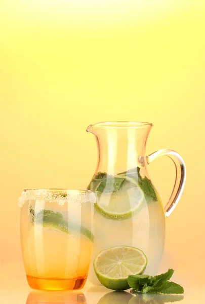 Limonade in Krug und Glas auf gelbem Hintergrund — Stockfoto