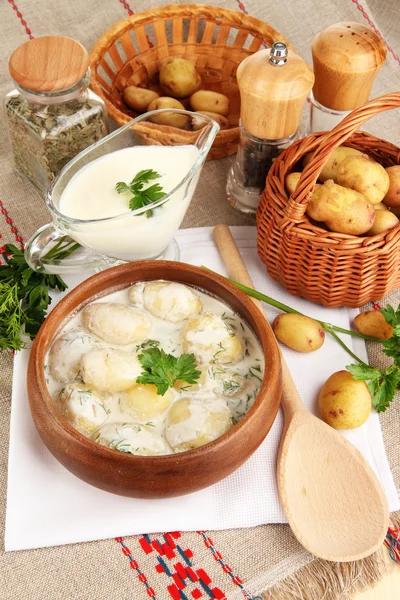 Tender young potatoes with sour cream and herbs in wooden bowl on tablecloth close-up — Stock Photo, Image