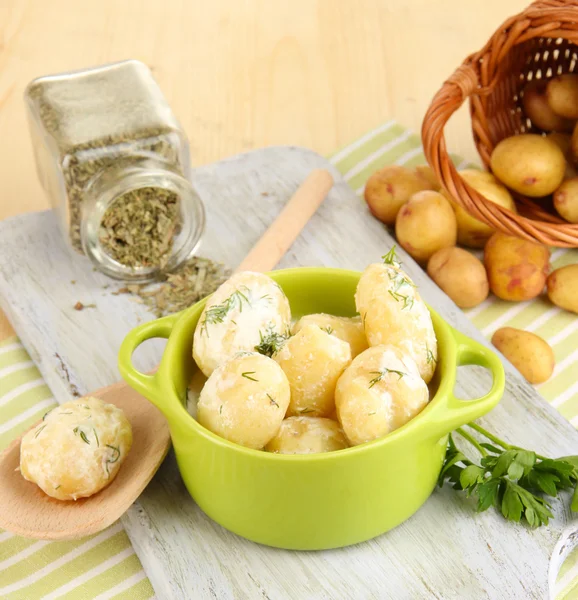 Jeunes pommes de terre tendres à la crème sure et aux herbes dans une casserole sur une planche de bois sur une table close-up — Photo