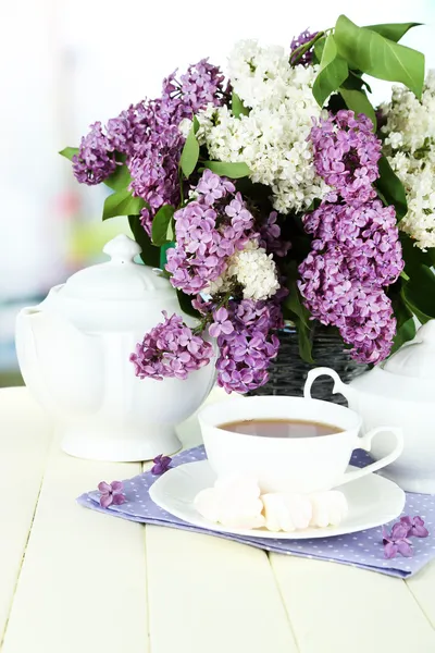 Composição com belas flores lilás, serviço de chá na mesa de madeira no fundo brilhante — Fotografia de Stock