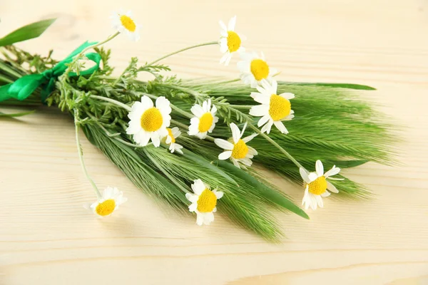 Green spikelets and wild camomiles, on wooden background — Stock Photo, Image