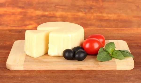 Cheese mozzarella,basil and vegetables on wooden background — Stock Photo, Image