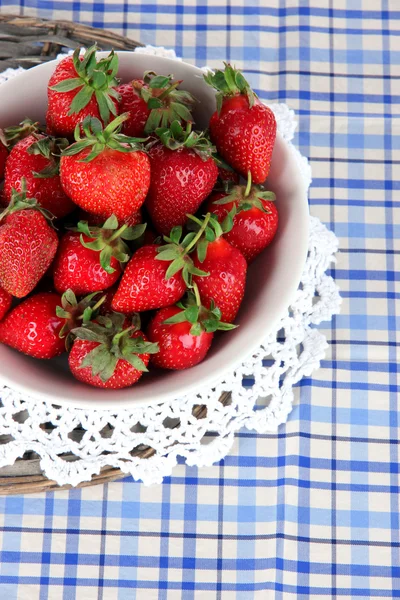 Strawberries in plate on wicker stand on napkin — Stock Photo, Image