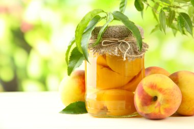 Dışarıda ahşap masa üzerinde kavanoz konserve şeftali ve taze şeftali