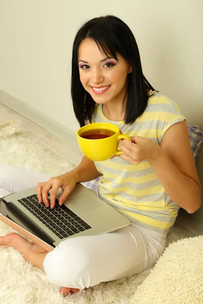 Belle jeune femme assise avec ordinateur portable dans la chambre — Photo