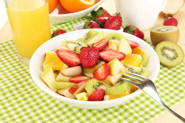 Nützlicher Obstsalat aus frischen Früchten und Beeren in Schüssel auf Serviette auf Holztisch Großaufnahme — Stockfoto