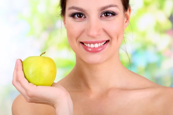 Donna sorridente con mela su sfondo luminoso — Foto Stock