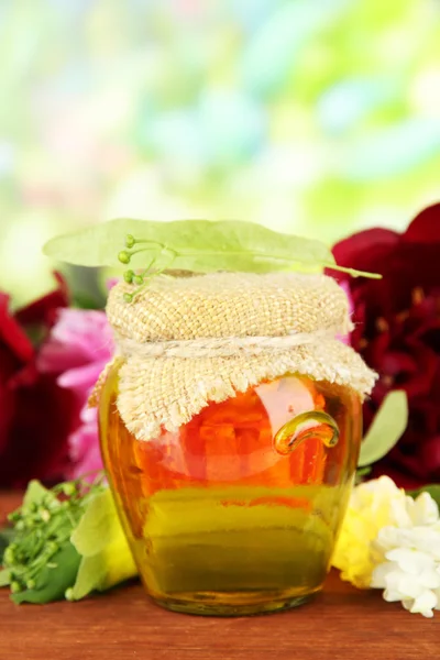 Jar of honey with flowers of lime, acacia, peony on wooden table, on bright background — Stock Photo, Image