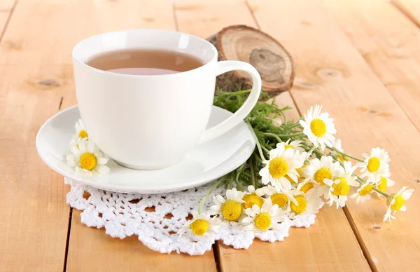 Cup of chamomile tea and chamomile on wooden table — Stock Photo, Image