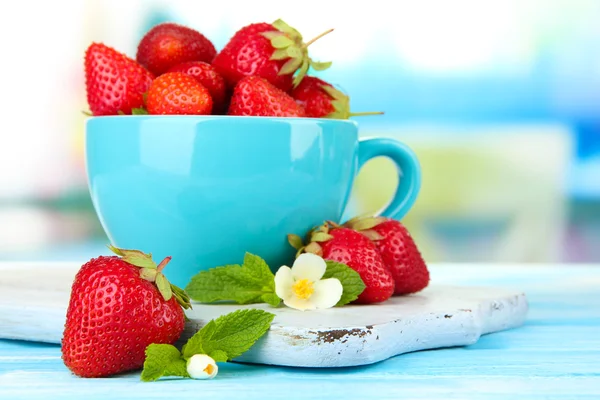 Zralé sladké jahody v poháru na modré dřevěný stůl — Stock fotografie