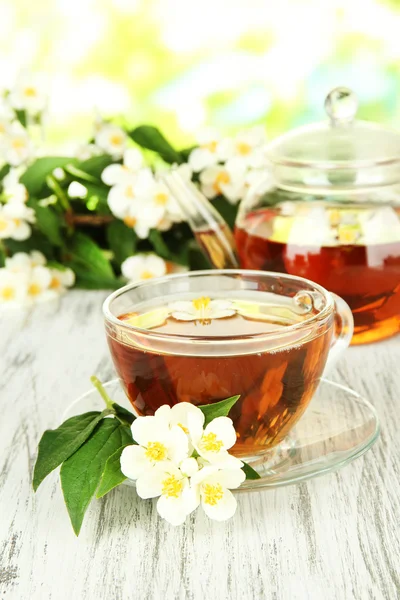 Cup of tea with jasmine, on wooden table, on bright background — Stock Photo, Image