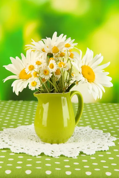 Beautiful bouquet chamomiles in pitcher on tablecloth on natural background — Stock Photo, Image