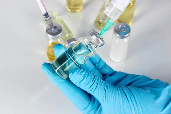 Medical bottles and syringes in hand on gray background — Stock Photo, Image