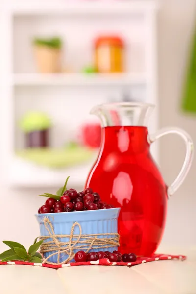 Pitcher of cranberry juice and red cranberries on table — Stock Photo, Image