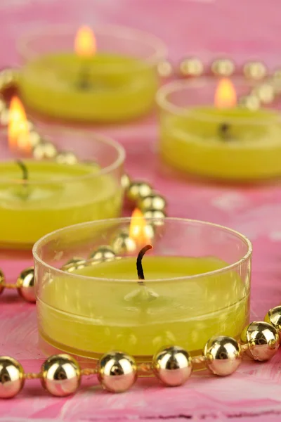 Lighted candles with beads on pink background — Stock Photo, Image