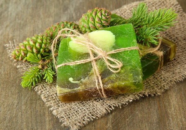 Hand-made soap and green pine cones on wooden background — Stock Photo, Image