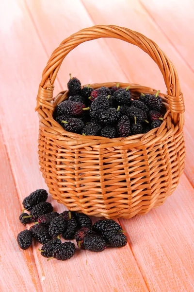 Reife Maulbeeren im Weidenkorb auf hölzernem Hintergrund — Stockfoto