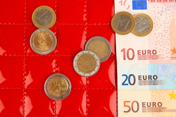 Eurobankbiljetten en eurocent op rode achtergrond — Stockfoto