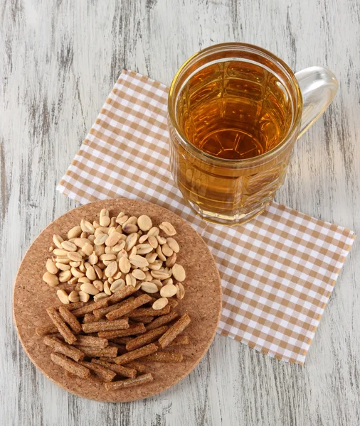 Beer in glass crunches, and nuts on napkin on wooden table — Stock Photo, Image