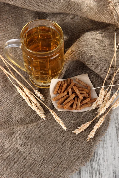 Cerveza en vaso y galletas en el embolsado en mesa de madera — Foto de Stock