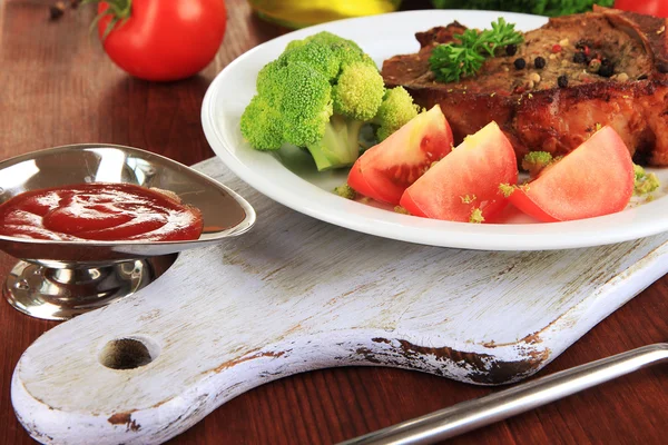 Stuk gebakken vlees op plaat op houten tafel close-up — Stockfoto