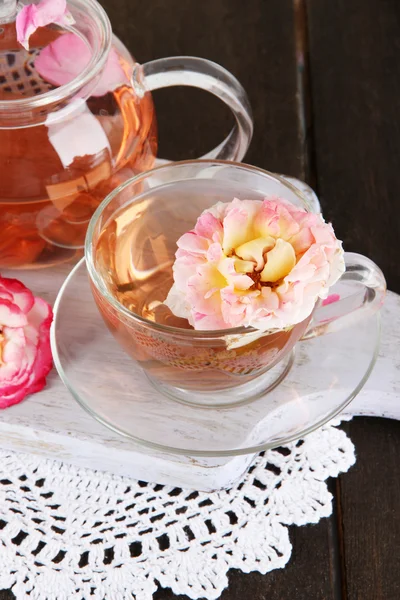 Vattenkokare och kopp te från tea rose ombord på servett på träbord — Stockfoto