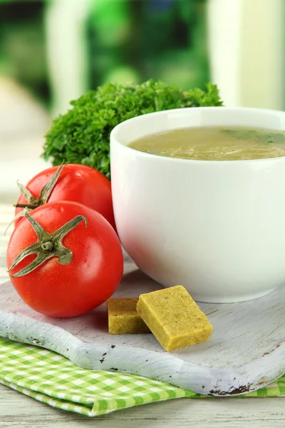 Cup of soup with bouillon cubes on wooden table — Stock Photo, Image