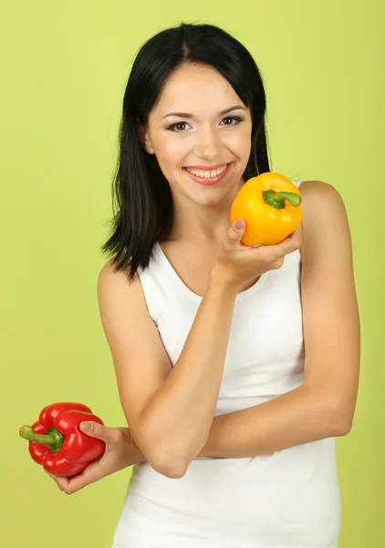 Flicka med färska paprika på grön bakgrund — Stockfoto