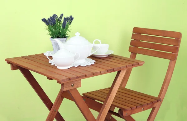 Mesa de madeira com configuração de mesa de chá sobre ele no fundo verde — Fotografia de Stock