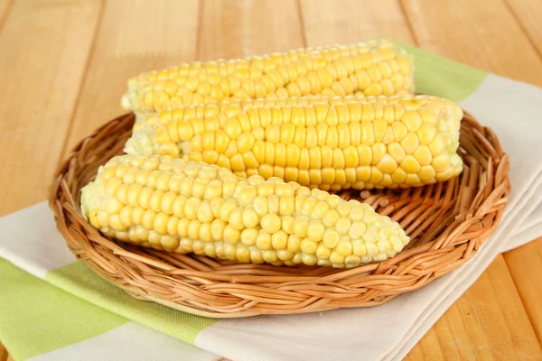 Fresh corn on wicker mat, on wooden background — Stock Photo, Image