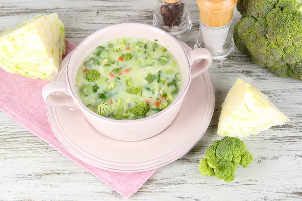 Cabbage soup in plate on napkin on wooden table — Stock Photo, Image