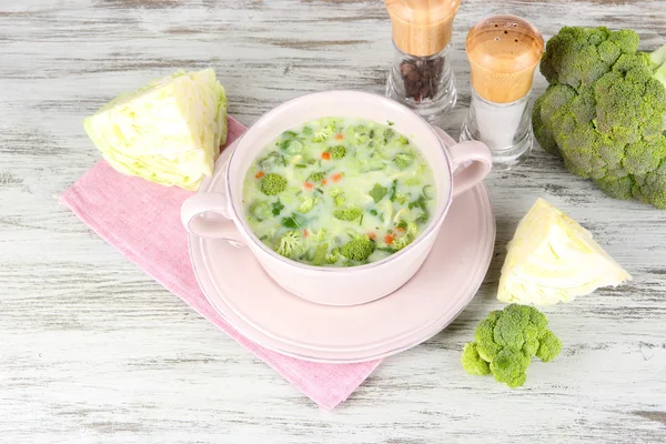 Cabbage soup in plate on napkin on wooden table — Stock Photo, Image