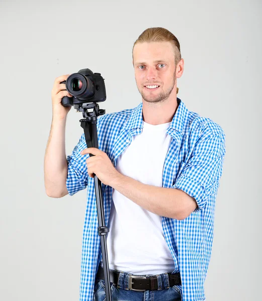 Fotógrafo bonito com câmera em monopod, em fundo cinza — Fotografia de Stock