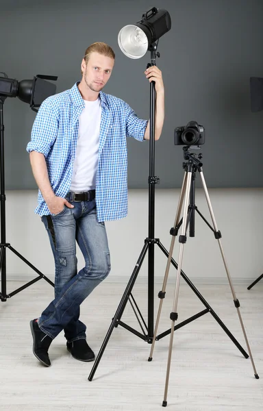 Fotógrafo guapo con cámara en el trabajo, sobre fondo de estudio fotográfico — Foto de Stock
