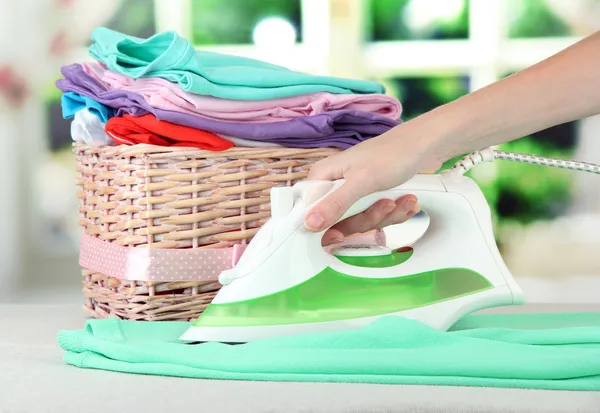 Woman's hand ironing clothes, on bright background — Stock Photo, Image