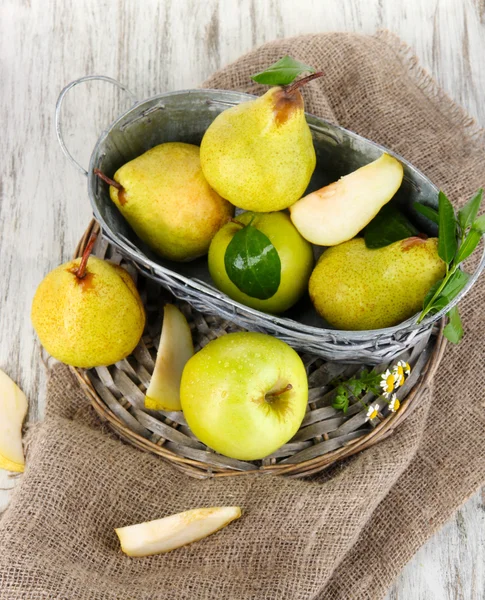 Pears in basket on braided tray on burlap on wooden table — Stock Photo, Image